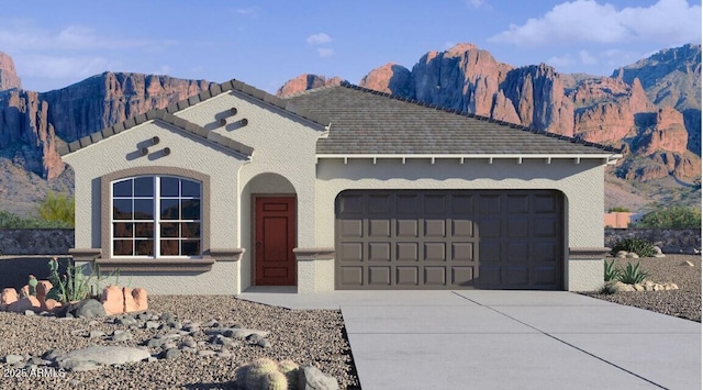 mediterranean / spanish home featuring concrete driveway, stucco siding, a mountain view, and a garage