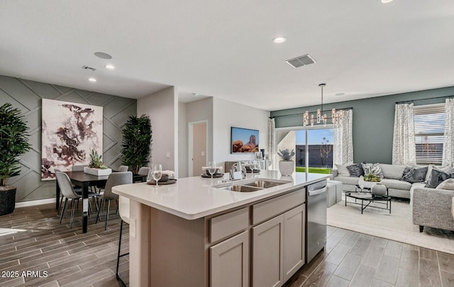 kitchen featuring stainless steel dishwasher, a sink, wood finish floors, and open floor plan