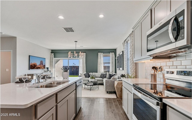 kitchen featuring a sink, a chandelier, stainless steel appliances, open floor plan, and visible vents