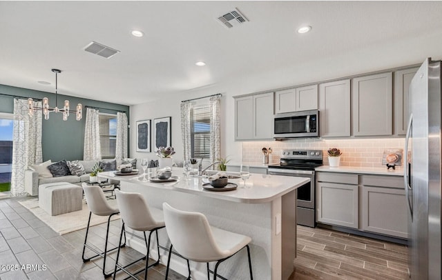kitchen with gray cabinetry, stainless steel appliances, a sink, and visible vents