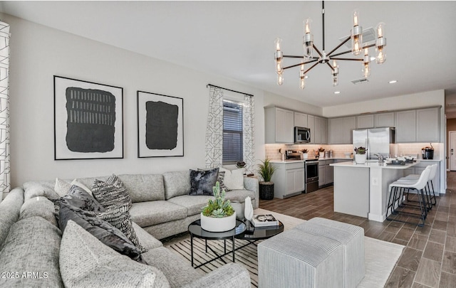 living room featuring recessed lighting, wood finish floors, an inviting chandelier, and visible vents
