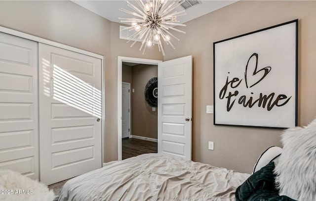 bedroom with an inviting chandelier, wood finished floors, and a closet