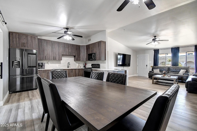 dining space with visible vents, baseboards, ceiling fan, vaulted ceiling, and light wood-style floors