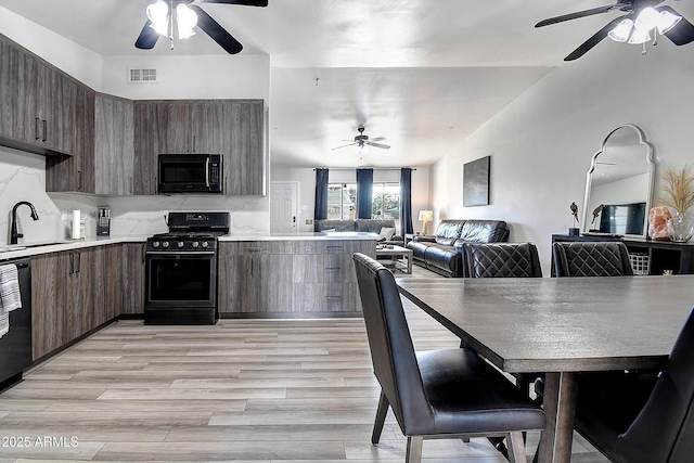 kitchen with visible vents, open floor plan, light countertops, black appliances, and modern cabinets