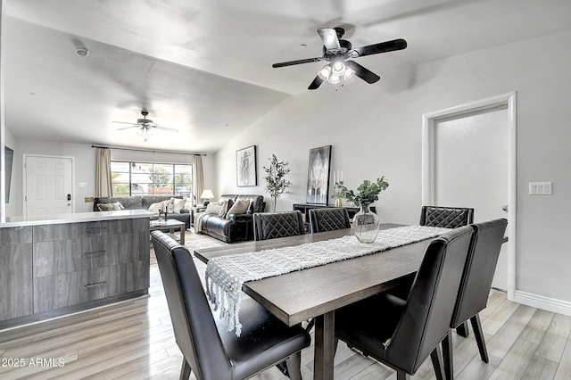 dining room with ceiling fan, light wood finished floors, vaulted ceiling, and baseboards