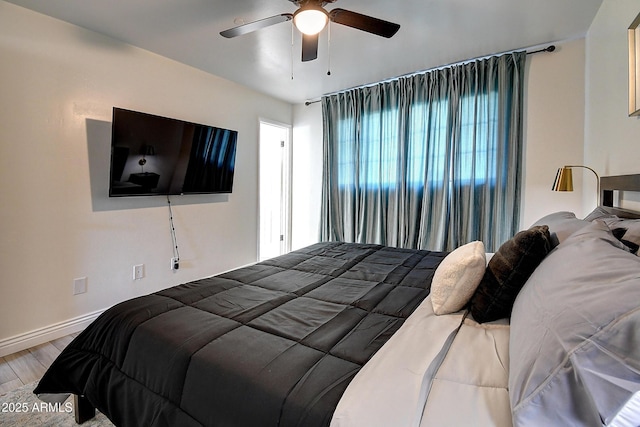 bedroom with ceiling fan, baseboards, and wood finished floors