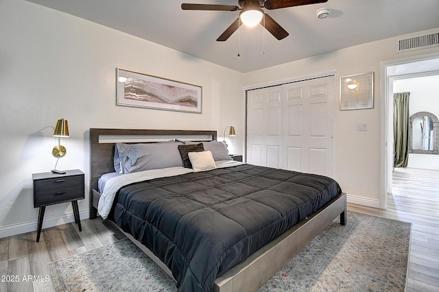 bedroom featuring a ceiling fan, visible vents, baseboards, a closet, and light wood finished floors