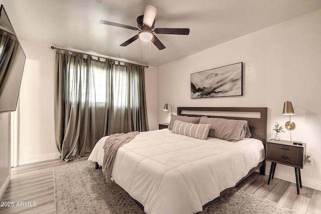 bedroom with a ceiling fan, baseboards, and light wood finished floors