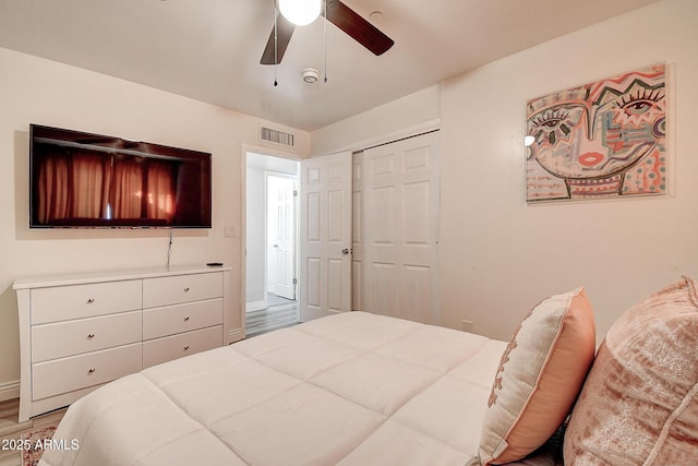 bedroom with a ceiling fan, a closet, visible vents, and wood finished floors