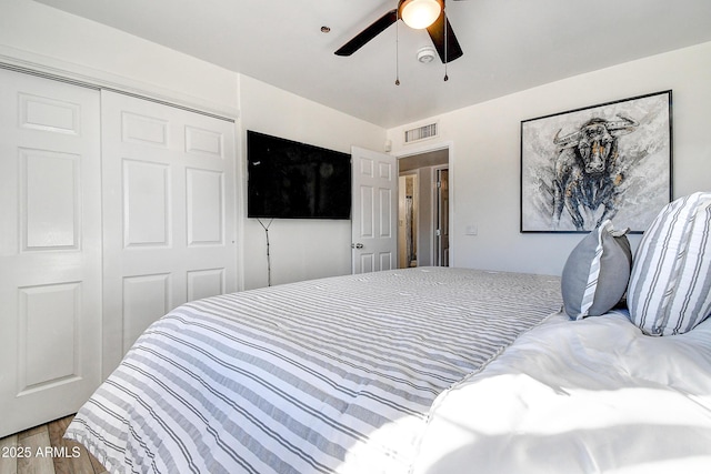 bedroom featuring ceiling fan, a closet, wood finished floors, and visible vents