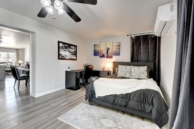 bedroom featuring a ceiling fan, light wood-type flooring, baseboards, and a wall mounted AC