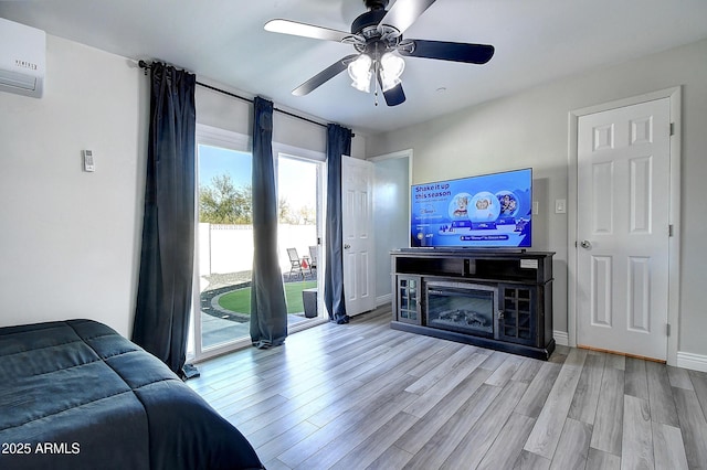 bedroom with baseboards, a ceiling fan, wood finished floors, access to outside, and a wall mounted AC