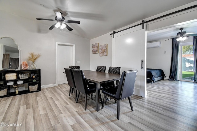 dining space with ceiling fan, lofted ceiling, a barn door, a wall mounted AC, and light wood finished floors