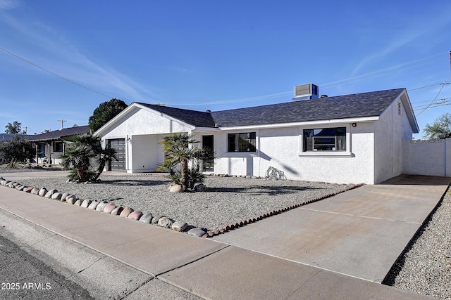 ranch-style home with concrete driveway, roof with shingles, and stucco siding