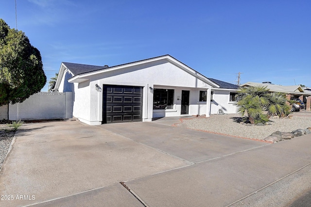 ranch-style house with driveway, an attached garage, fence, and stucco siding