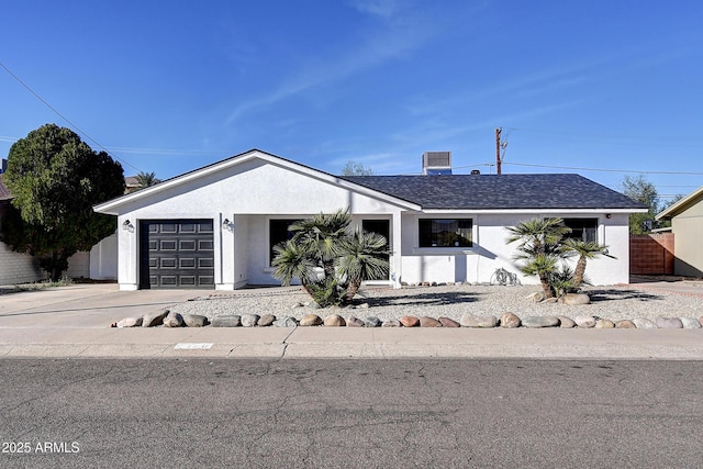 view of front of home with a garage, concrete driveway, fence, and stucco siding