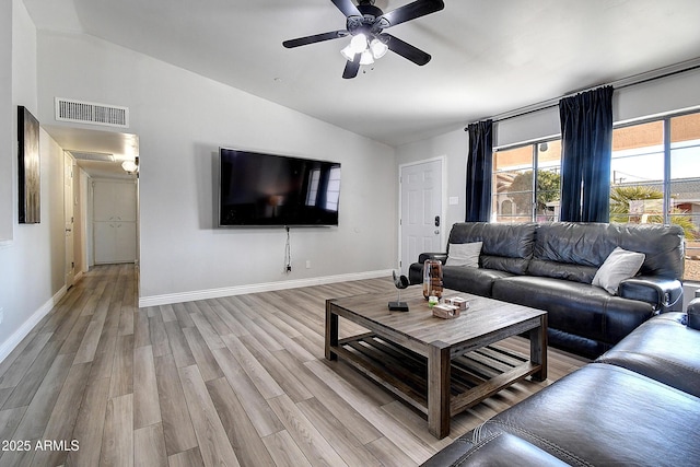 living area with baseboards, visible vents, vaulted ceiling, and light wood finished floors