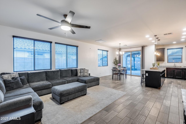 living room with ceiling fan with notable chandelier