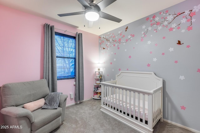 bedroom with a nursery area, light carpet, and ceiling fan