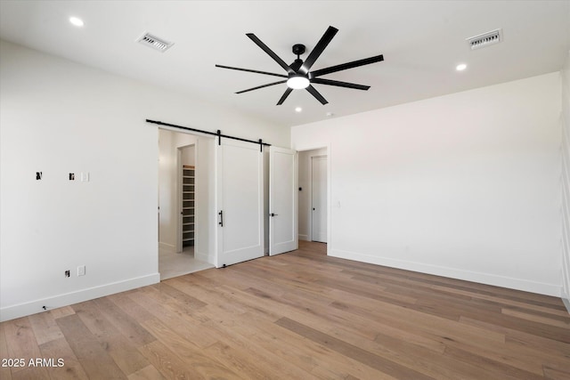 3323 N 81st St, Mesa, AZ 85207 - unfurnished bedroom featuring a barn door, light wood-style floors, baseboards, recessed lighting, and a walk in closet