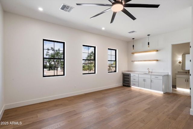 3323 N 81st St, Mesa, AZ 85207 - unfurnished living room featuring wine cooler, wet bar, a ceiling fan, light wood-type flooring, and baseboards