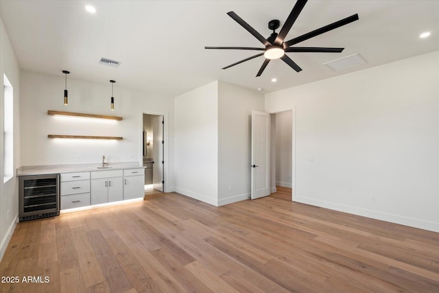 3323 N 81st St, Mesa, AZ 85207 - unfurnished living room with beverage cooler, bar with sink, a ceiling fan, light wood-style flooring, and baseboards