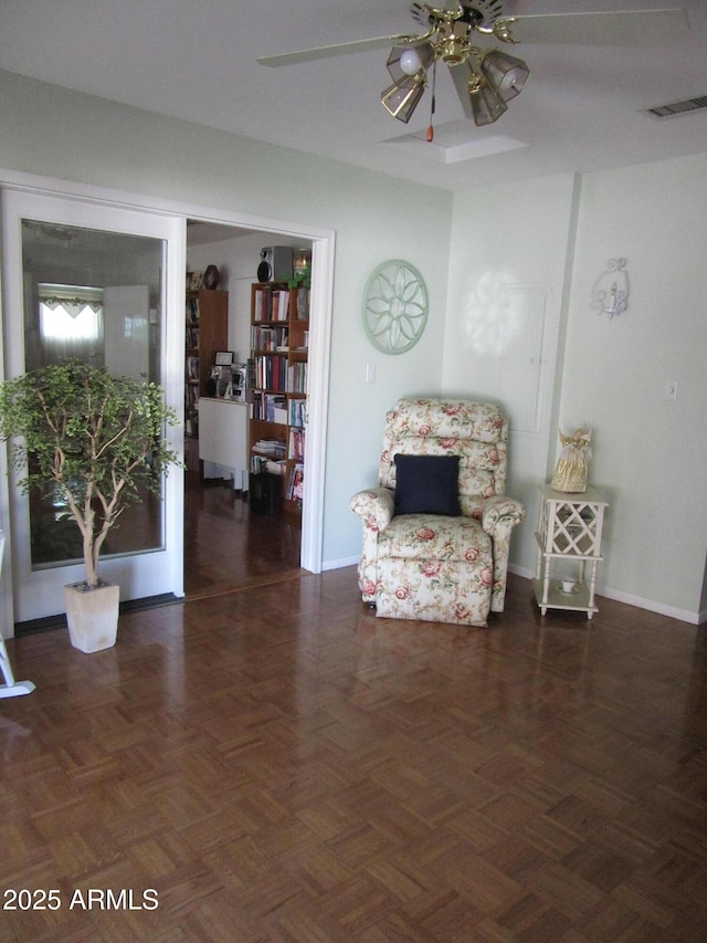 sitting room with ceiling fan and dark parquet floors