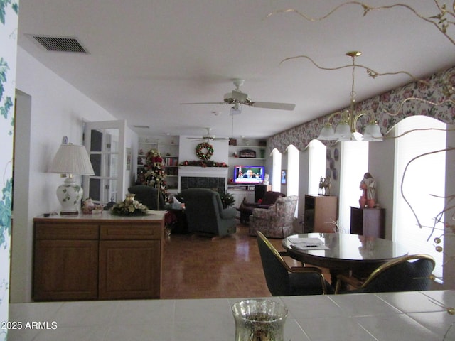 dining area with a tile fireplace and ceiling fan