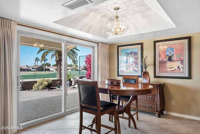 dining room featuring an inviting chandelier, a textured ceiling, visible vents, and a tray ceiling