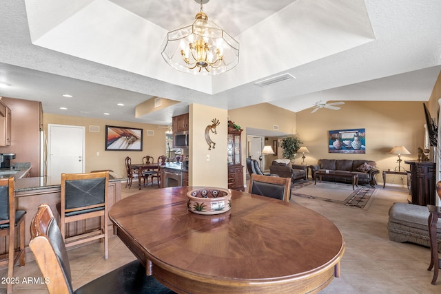 dining room with light tile patterned floors, lofted ceiling, a raised ceiling, visible vents, and ceiling fan with notable chandelier