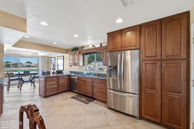 kitchen featuring a peninsula, a sink, visible vents, appliances with stainless steel finishes, and brown cabinets