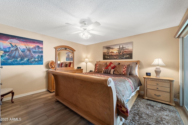 bedroom featuring a ceiling fan, dark wood-style flooring, a textured ceiling, and baseboards