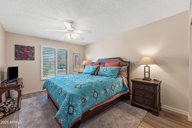 bedroom with ceiling fan, a textured ceiling, baseboards, and wood finished floors