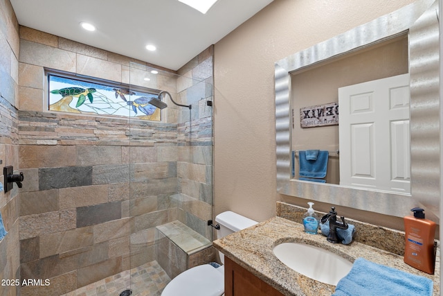 bathroom featuring a textured wall, vanity, a shower stall, and toilet