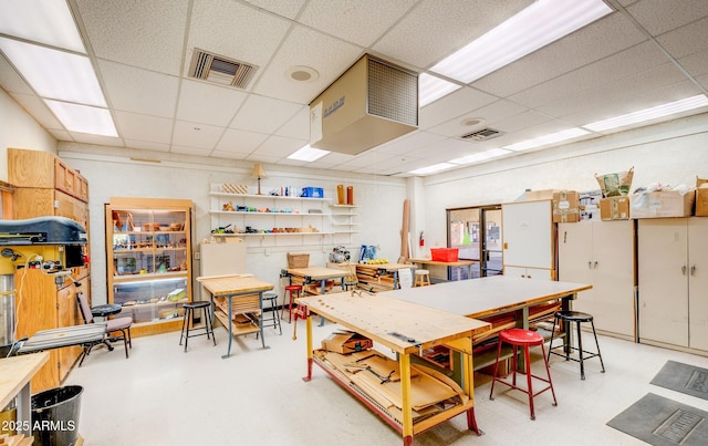 interior space featuring light floors, a drop ceiling, and visible vents