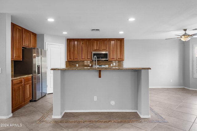 kitchen featuring backsplash, light stone countertops, a kitchen breakfast bar, and appliances with stainless steel finishes