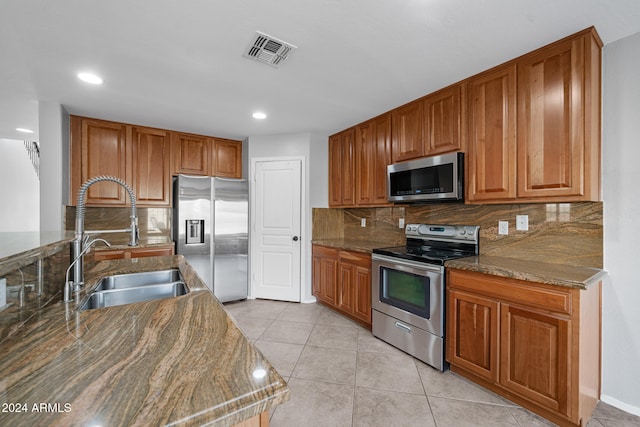 kitchen with decorative backsplash, appliances with stainless steel finishes, dark stone countertops, and sink