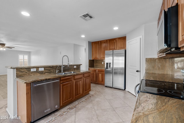 kitchen with stone counters, sink, decorative backsplash, ceiling fan, and appliances with stainless steel finishes