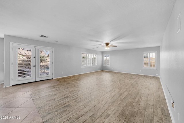 unfurnished room with french doors, light wood-type flooring, a wealth of natural light, and ceiling fan