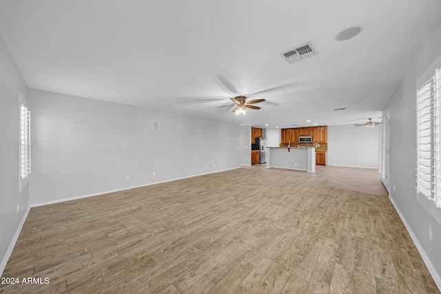 unfurnished living room with light wood-type flooring and ceiling fan