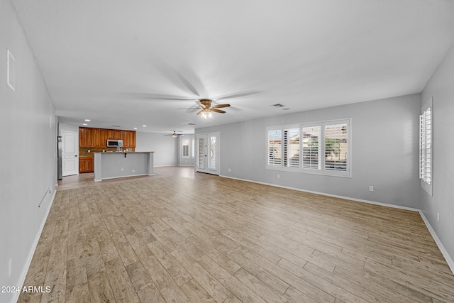 unfurnished living room featuring ceiling fan and light hardwood / wood-style flooring