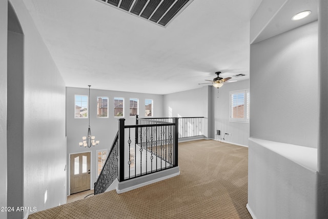 hall with light carpet, plenty of natural light, and a chandelier