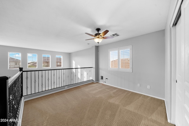 carpeted empty room with ceiling fan and a healthy amount of sunlight