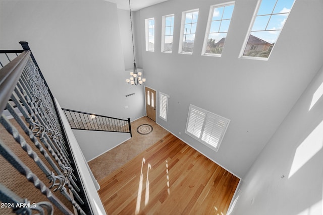 stairway with hardwood / wood-style floors, a notable chandelier, and a high ceiling