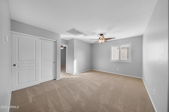 unfurnished bedroom featuring ceiling fan, a closet, and light carpet