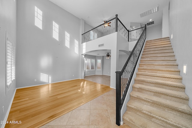 entrance foyer featuring ceiling fan, a towering ceiling, and light hardwood / wood-style flooring