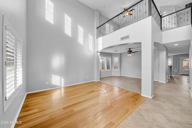 unfurnished living room featuring a high ceiling, light hardwood / wood-style floors, and ceiling fan