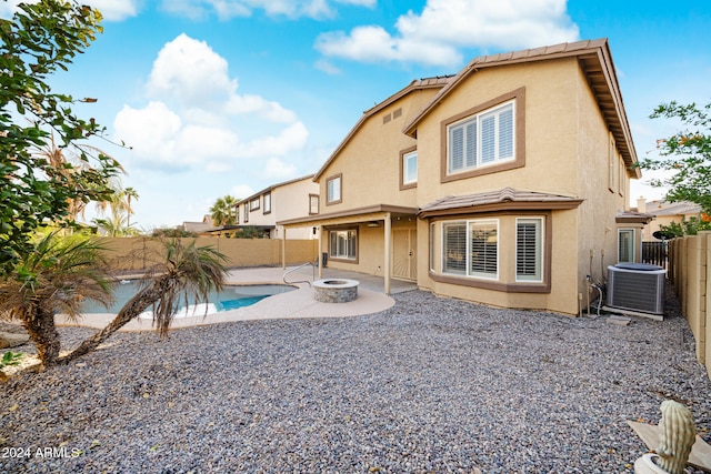 back of property with a patio area, a fenced in pool, an outdoor fire pit, and central AC