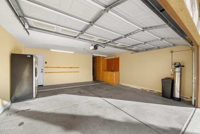 garage featuring stainless steel refrigerator and a garage door opener