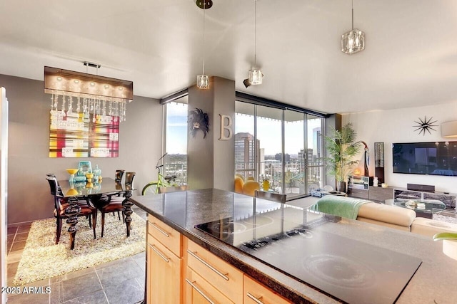 kitchen featuring open floor plan, black electric stovetop, light brown cabinets, and a healthy amount of sunlight